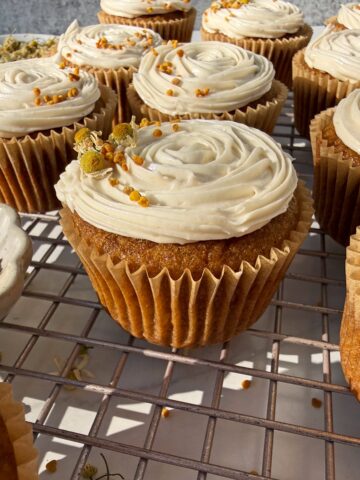 Cupcakes decorated with paleo vanilla frosting, bee pollen and edible flowers.