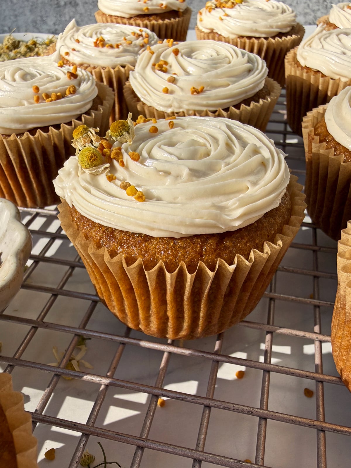 Cupcakes decorated with paleo vanilla frosting, bee pollen and edible flowers.