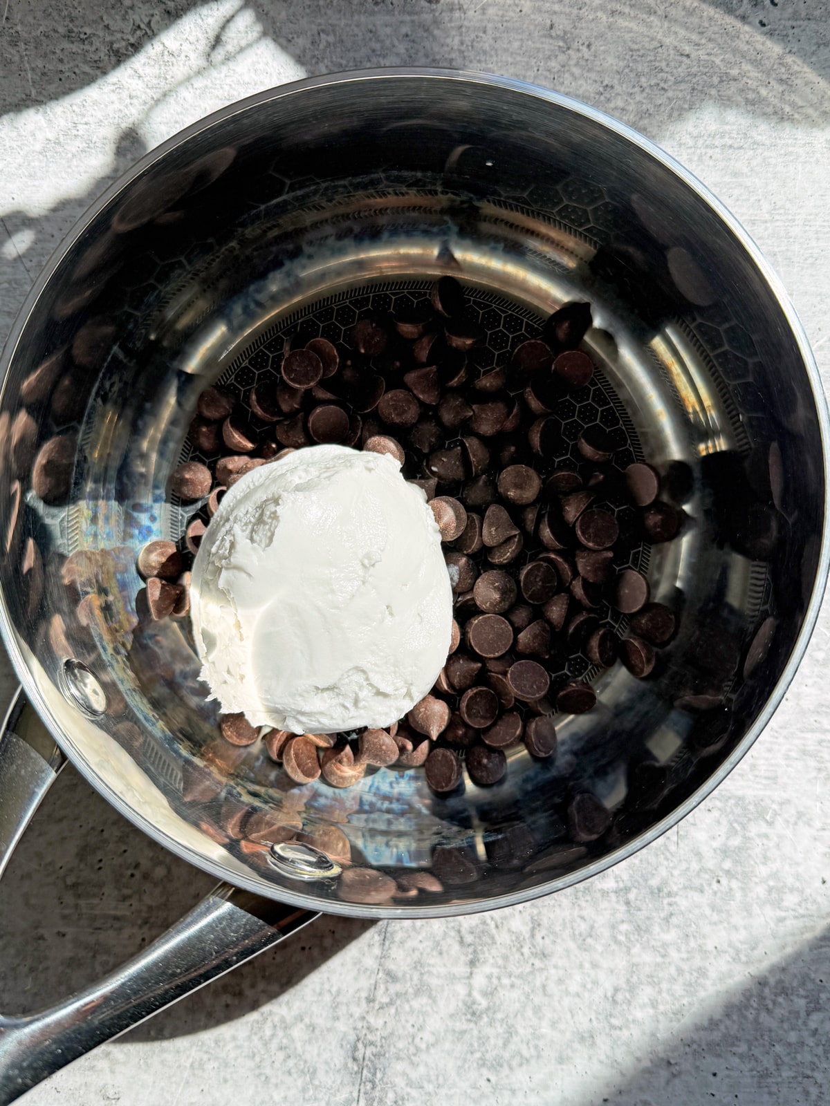Coconut cream and chocolate in a saucepan, ready to melt over the stovetop.