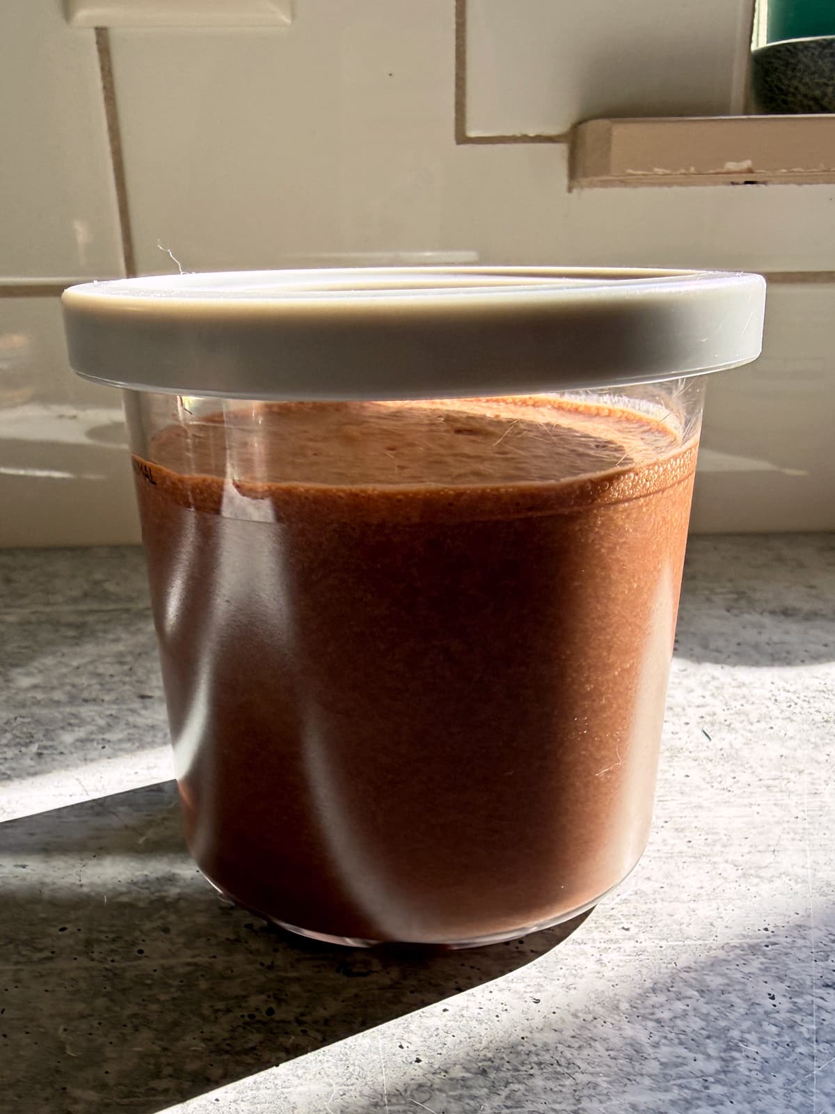 Blended ingredients for making chocolate hazelnut ice cream in a creami pint, ready to freeze.