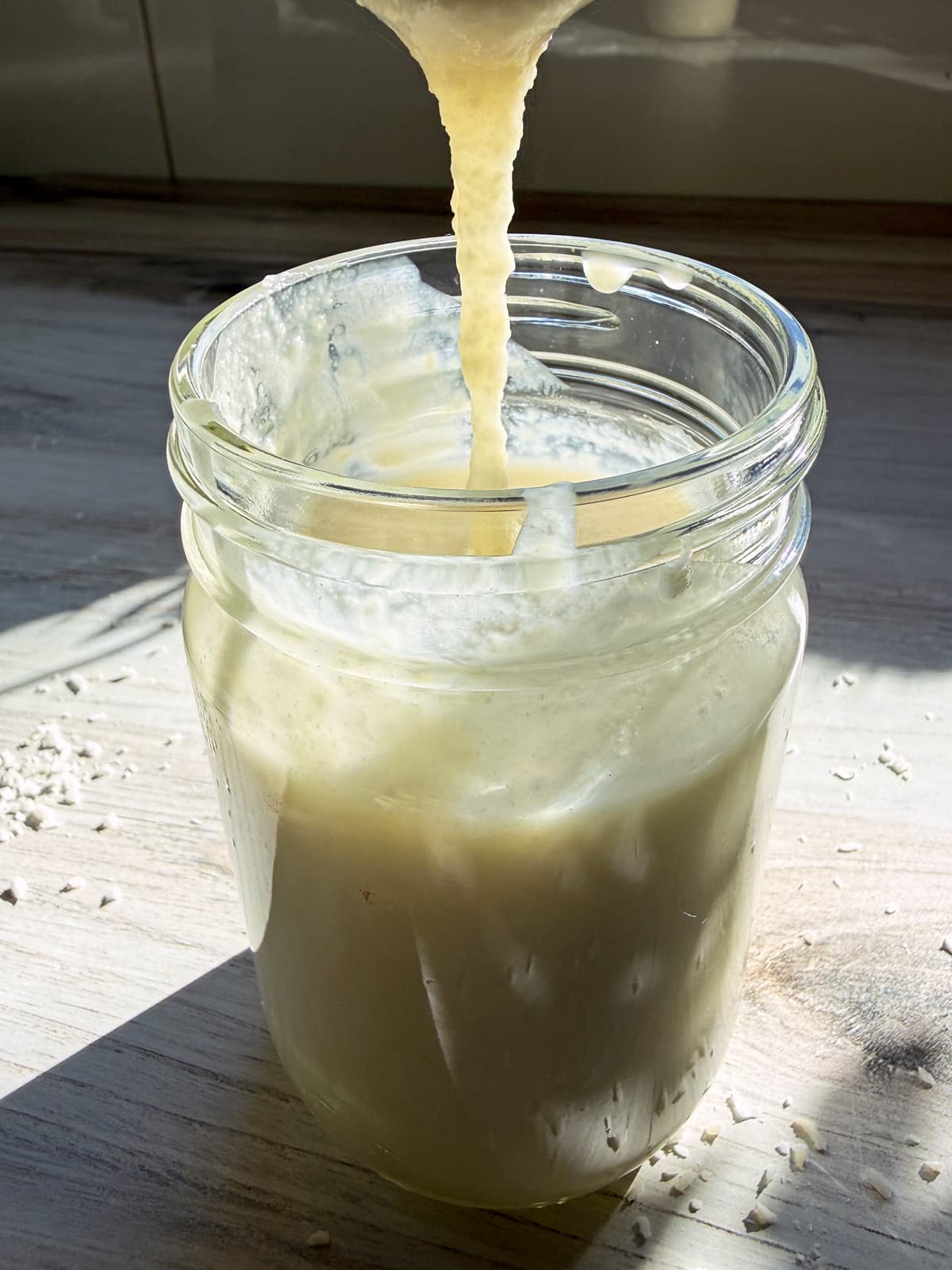 Pouring coconut butter into a jar.