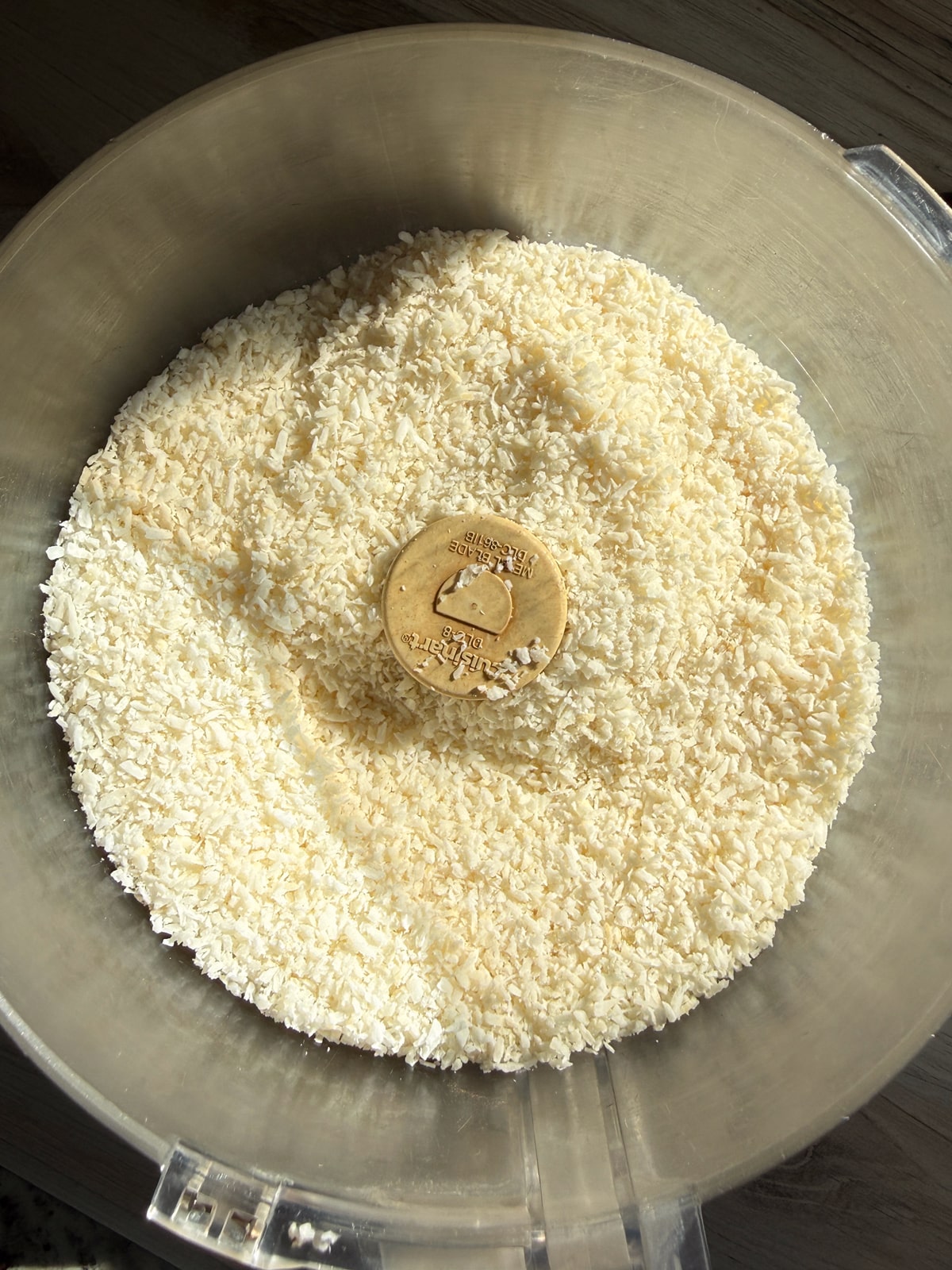 Shredded coconut in food processor, ready to blend.