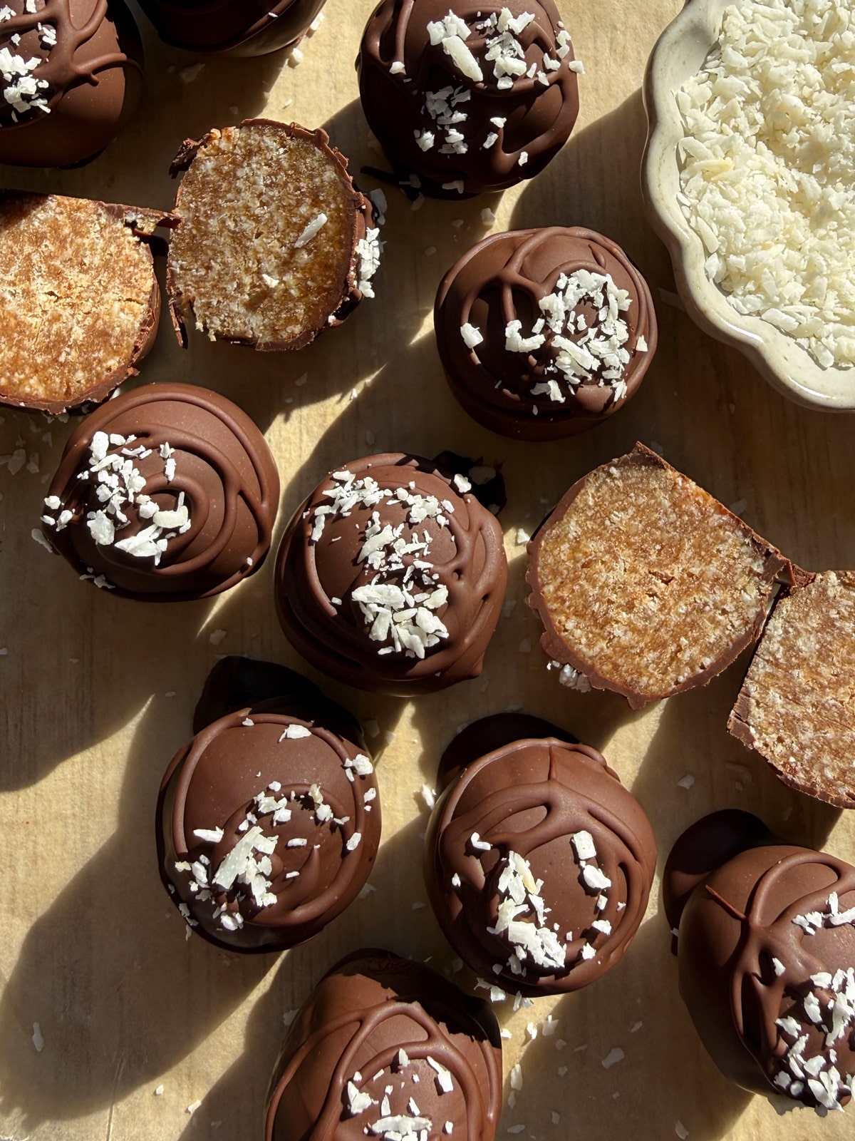 Coconut date balls dipped in chocolate and topped with shredded coconut.