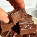Grabbing a piece of chocolate with a bite out of it.