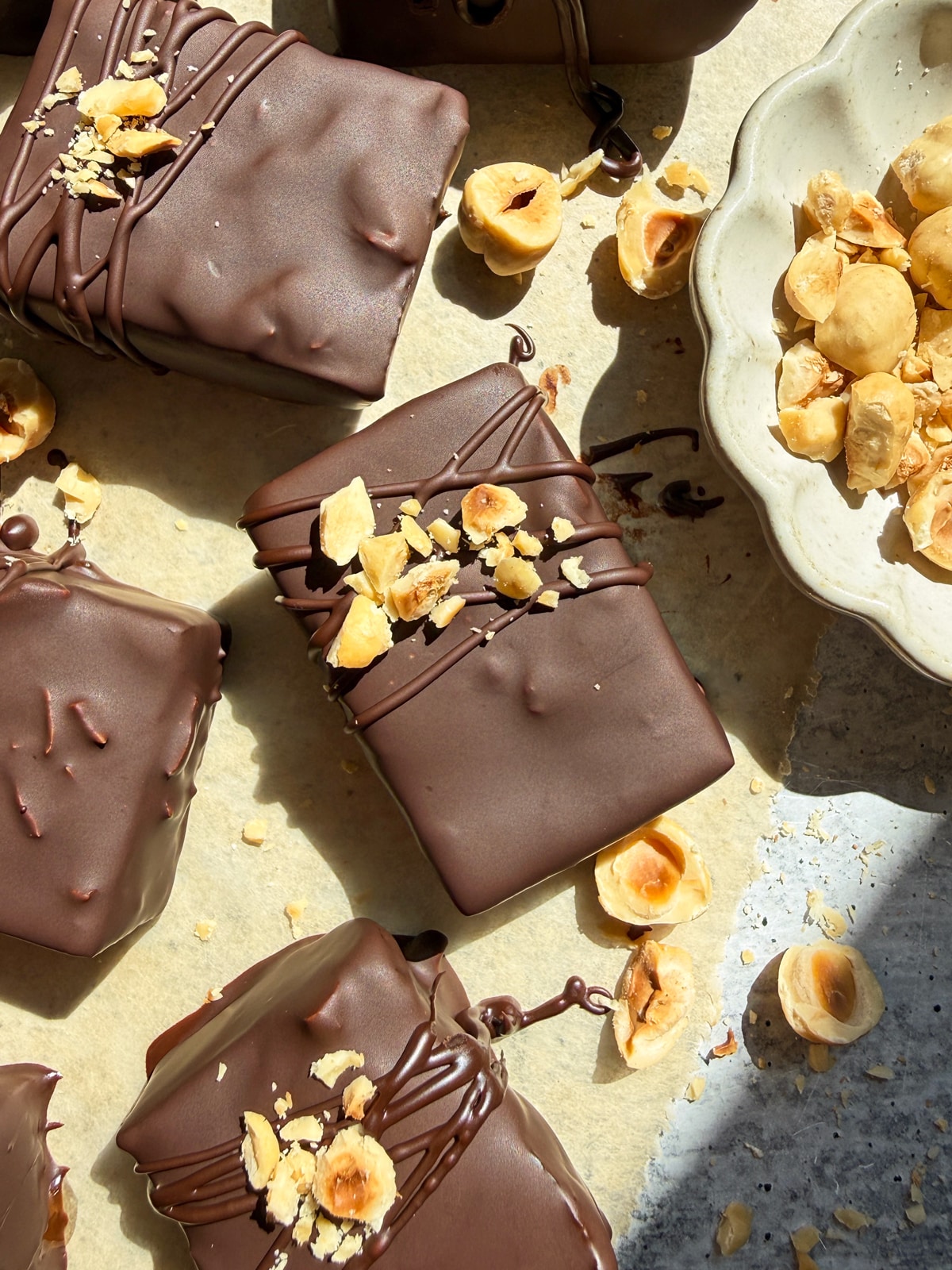 Hazelnut coffee bars coated in chocolate and topped with chopped hazelnuts.
