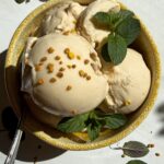 Bowl of ice cream topped with mint leaves and bee pollen.