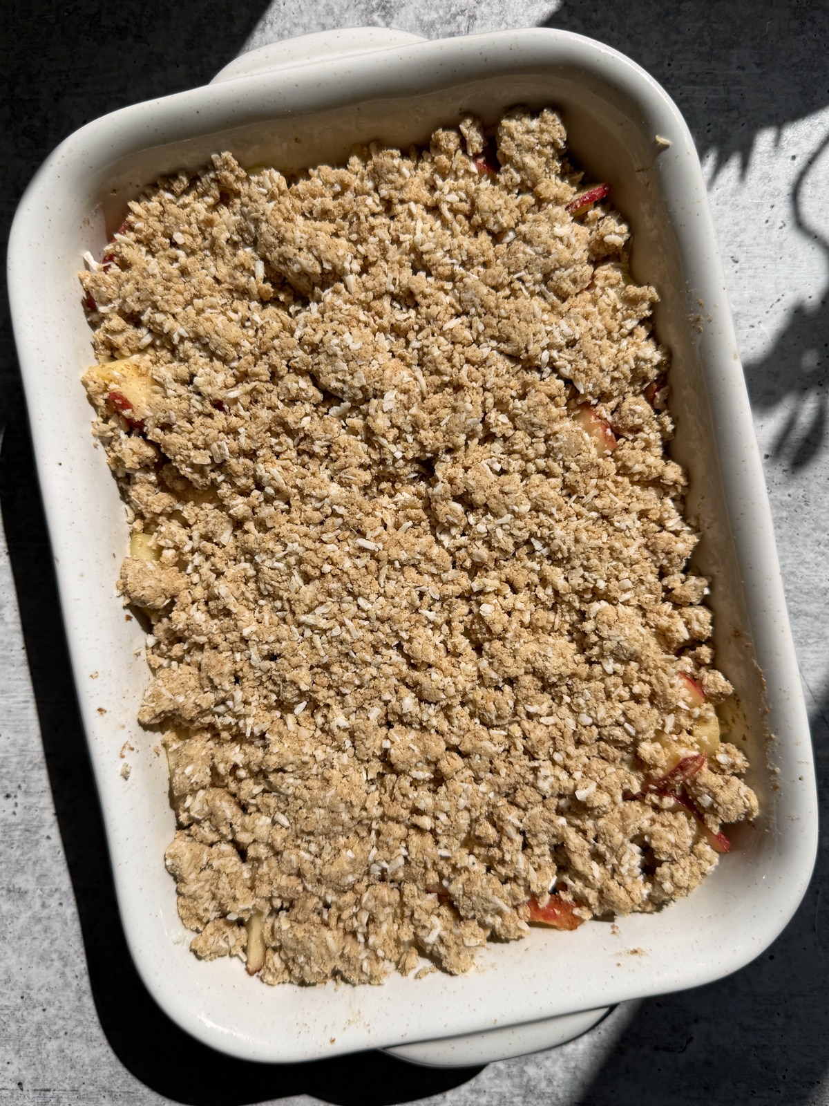 Unbaked apple crisp assembled in a baking dish, ready to bake in the oven.