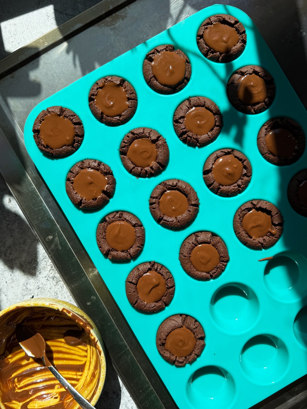 Adding the fudge filling to the cookie cups.