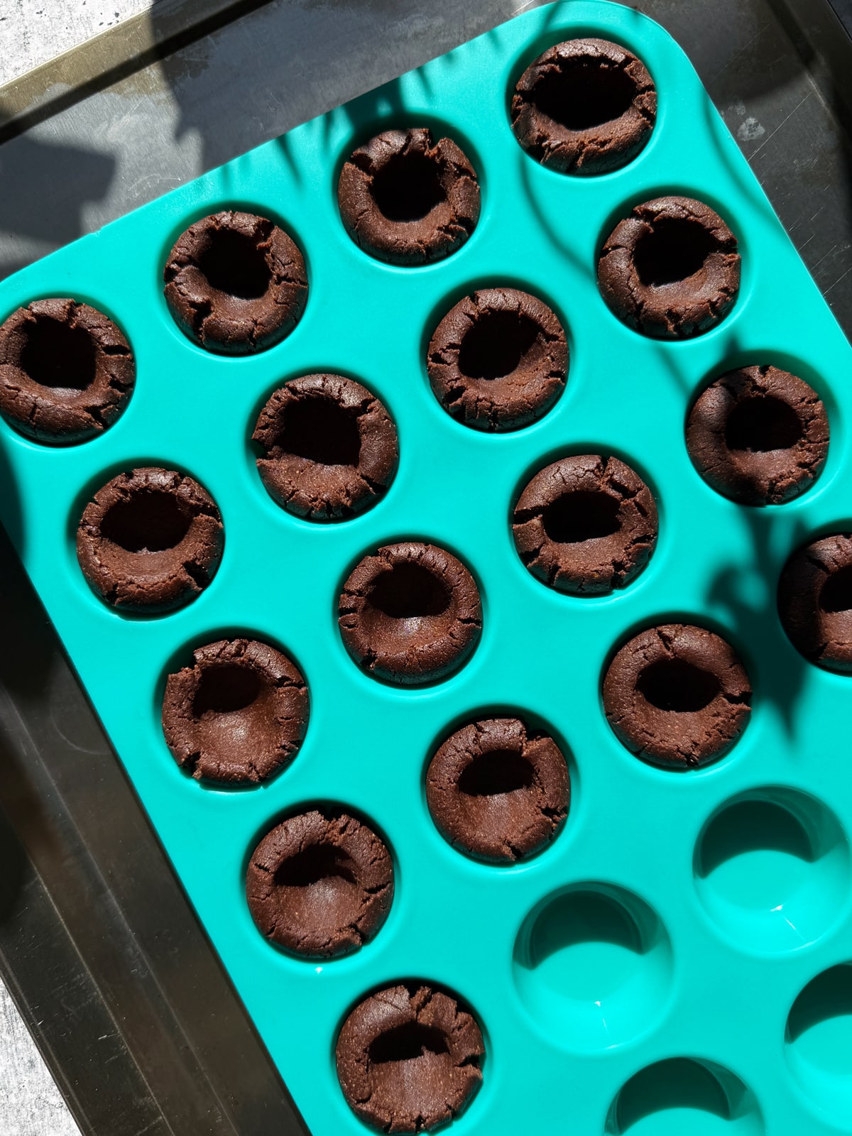Chocolate cookie cup dough in mini muffin pan, ready to bake.