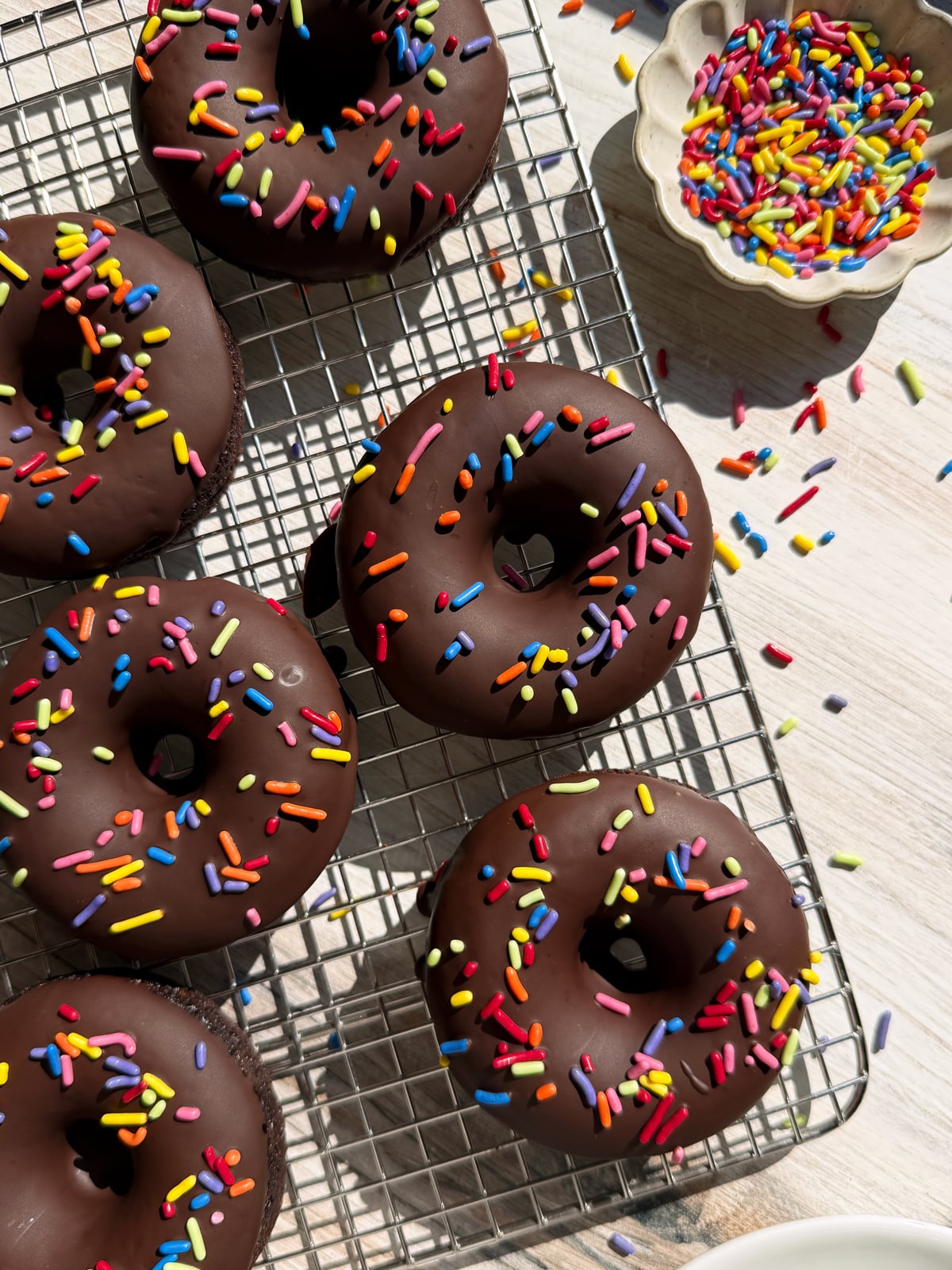 Baked and decorated donuts on wire cooling rack.