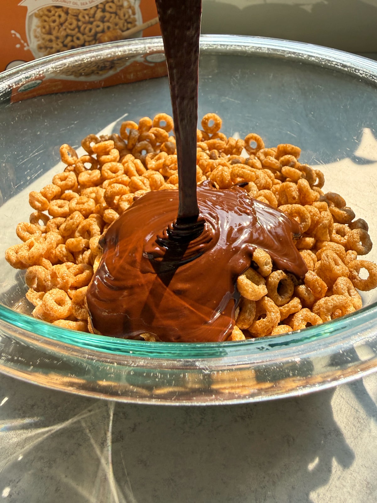 Pouring the almond butter and chocolate mixture on the cereal.
