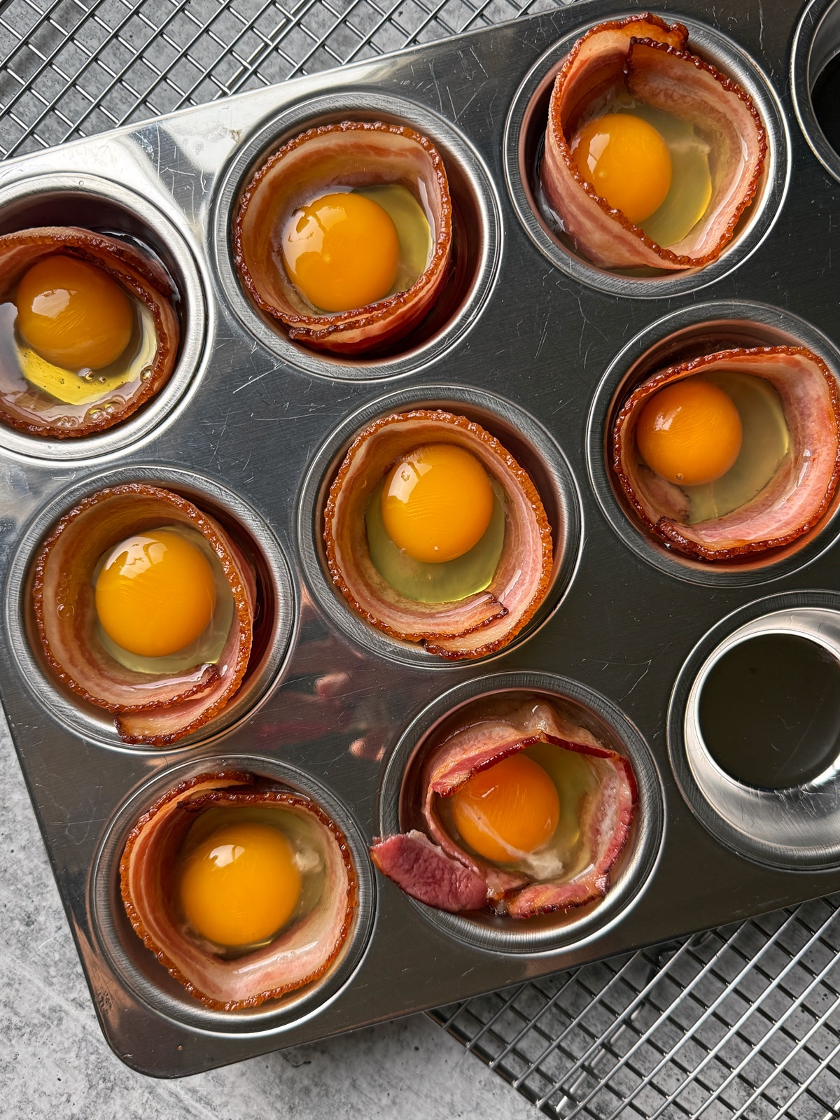 Bacon and eggs in a muffin tin, ready to bake in the oven.