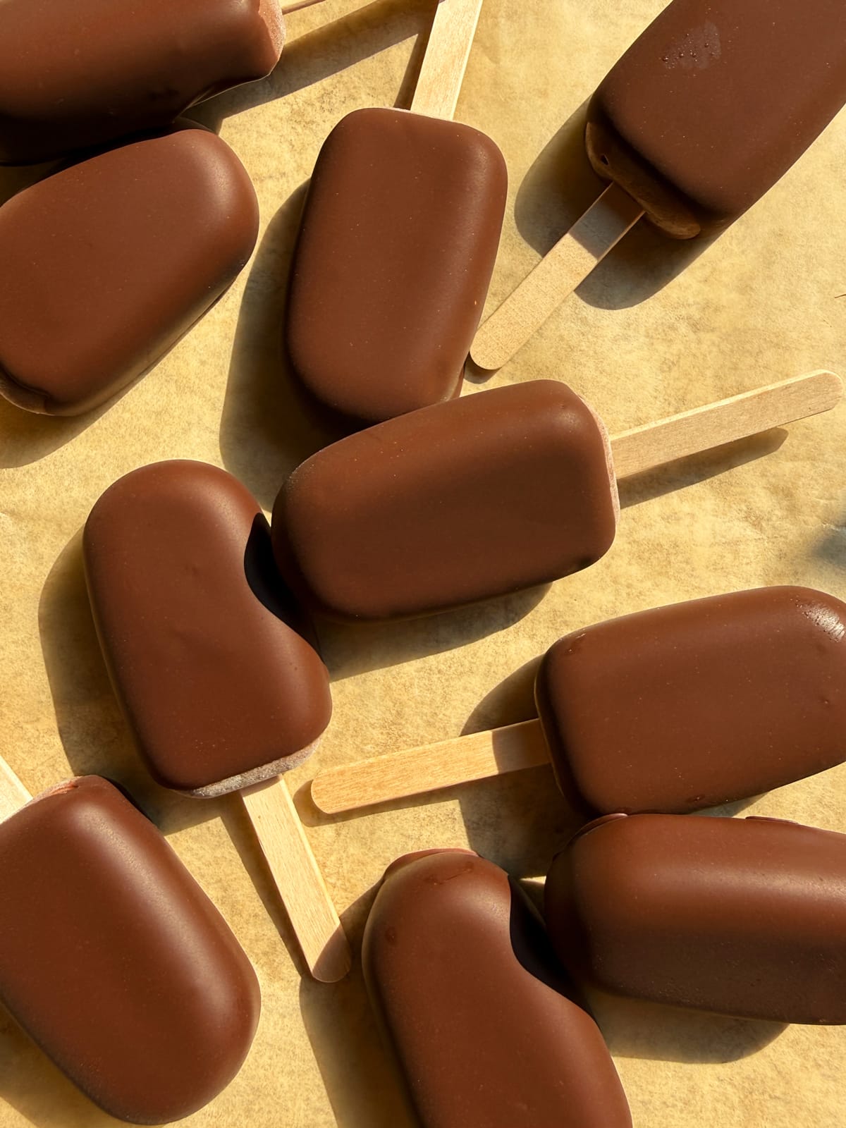 Chocolate dipped yogurt popsicles on parchment paper.