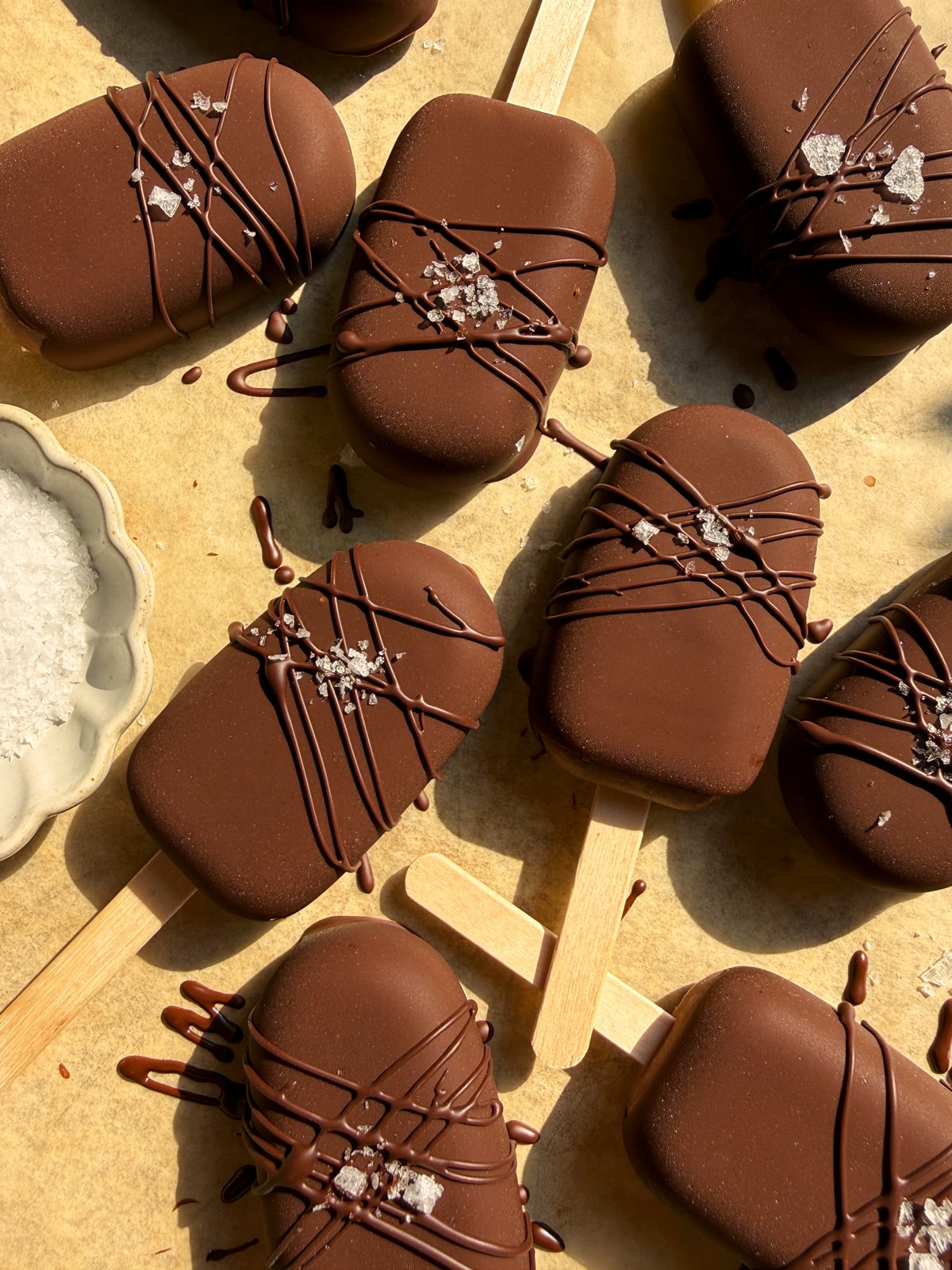 Top down view of popsicles decorated with a chocolate drizzle and flaked salt.
