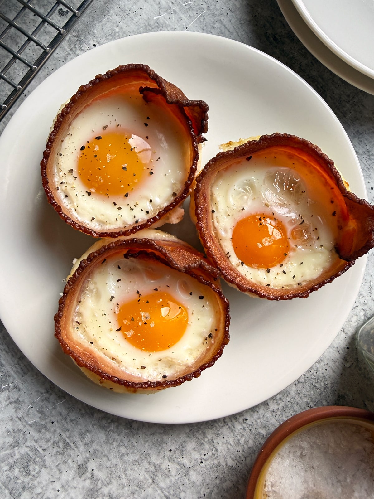 Top down view of three bacon egg cups on a plate.