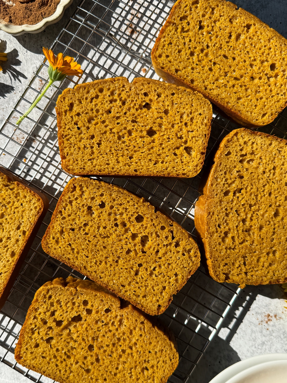 Top down view of sliced buckwheat pumpkin bread on wire cooling rack.