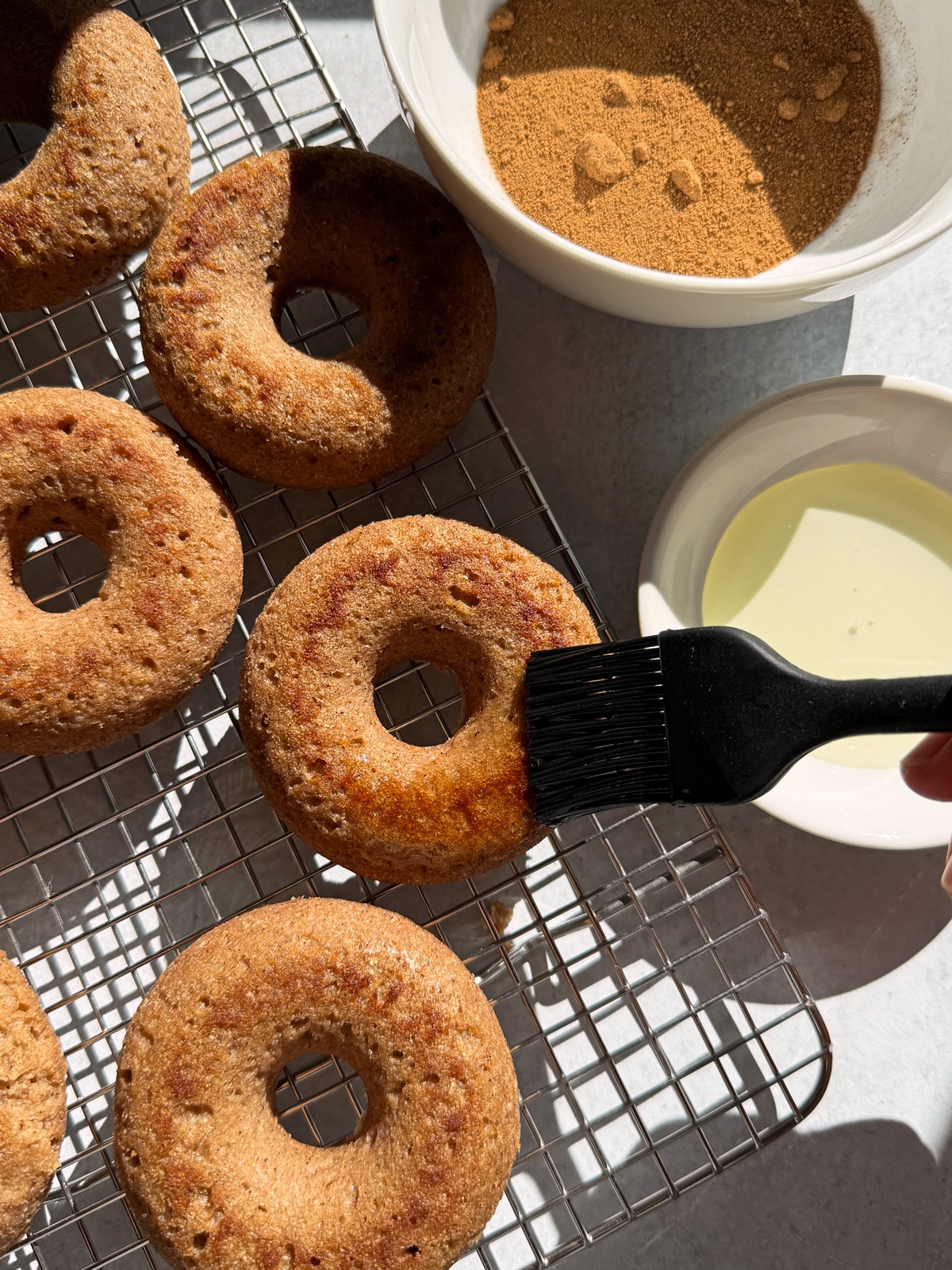 Brushing the tops of the donuts with oil.