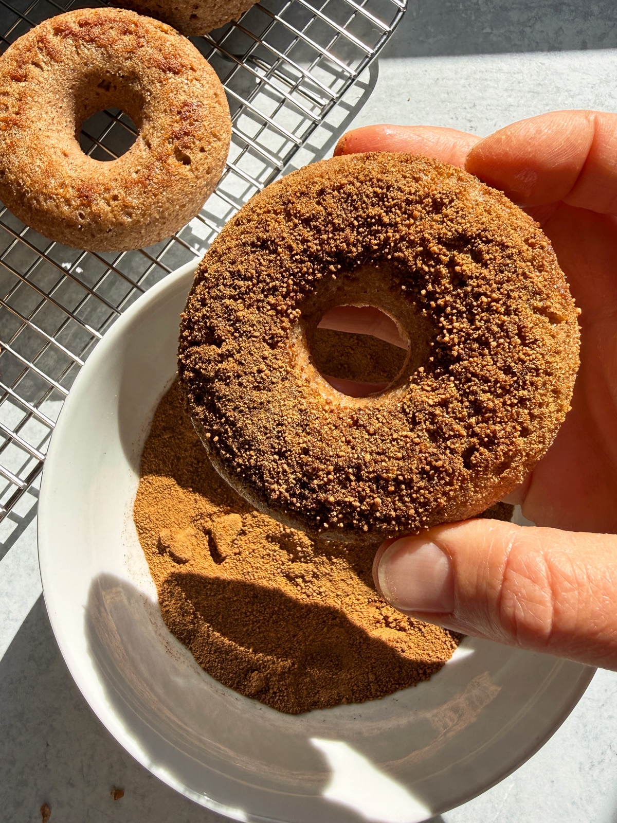 Dipping the donuts in the cinnamon sugar.