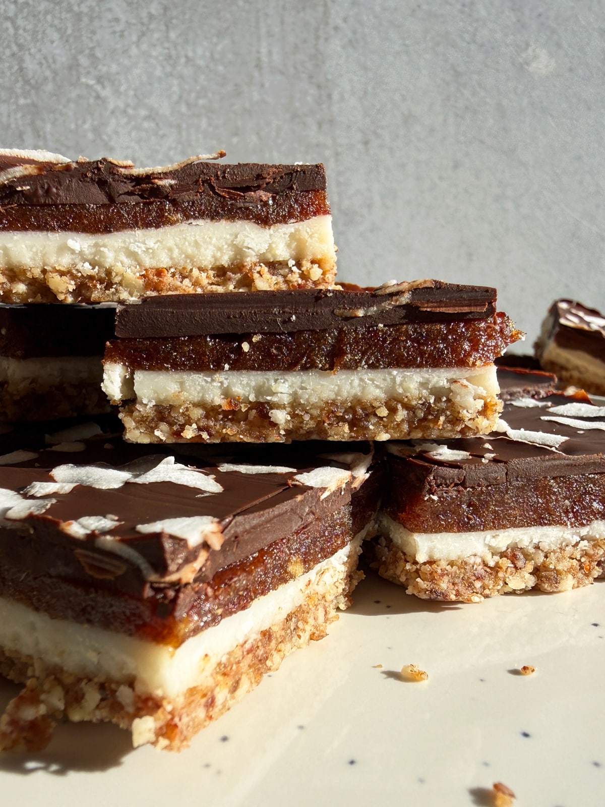 Side view of coconut butter bars stacked on a plate.