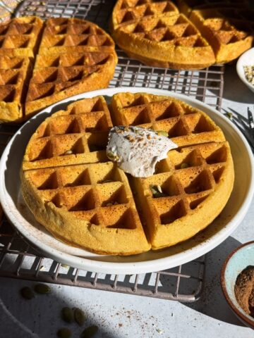 Paleo pumpkin waffles topped with coconut cream, bee pollen and pumpkin seeds.